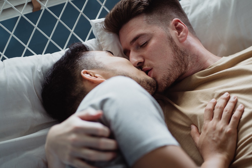 Two men kissing in bed